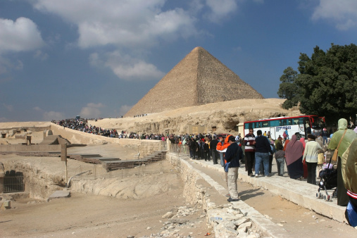 Cairo, Egypt - January 26, 2006: Crowds of local and international visitors walk along a modern road to the Great Pyramid of Giza, also called the Pyramid of Khufu, the oldest and largest of the three pyramids.