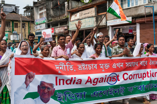 Jorhat, India - August 23, 2011: An anti-corruption march by supporters of the popular Indian politician, Anna Hazare. The supporters are marching with a large banner and waving the Indian tri-colour flag through the main high street in the city of Jorhat in Assam, north east India.