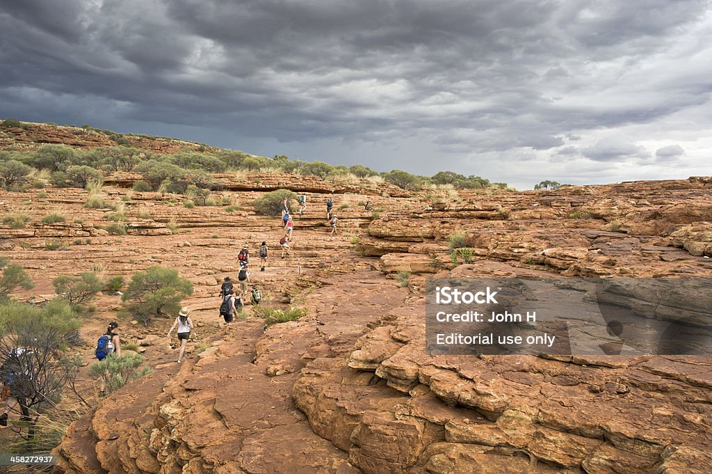 Hiking in the Kings Canyon,Northern Territory, Australia Alice Springs, Australia - February 16, 2011:Many tourists was hiking in the Kings Canyon,Northern Territory, Australia.Watarrka National Park encloses Kings Canyon, with its 300-metre-high sandstone walls, walking trails, lush forests and permanent waterholes. The sheer red rock face of the canyon soars above dense forests of palms, ferns and cycads, sheltering them from the harsh desert, and providing refuge for many native animals. Alice Springs Stock Photo