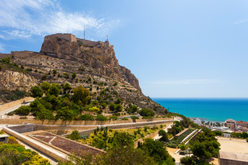 Alicante, Spain - August 19, 2011: View of the coastal city of Alicante with the Santa Barbara Castle overlooking the coastline and some local buildings below.