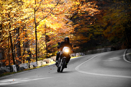Prahova, Romania - October 20, 2013: A motorcyclist on a winding road with autumnal background on October 20, 2013 in Prahova.