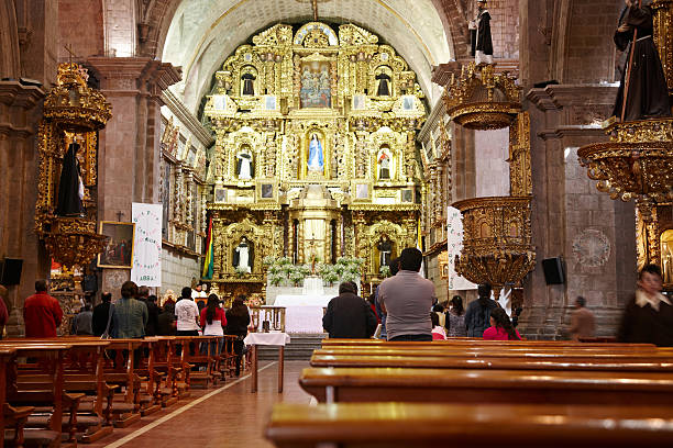 La Paz, Bolivia - May 30, 2013: Pews in the back of a La Paz church. People are pictured praying at the front of the building