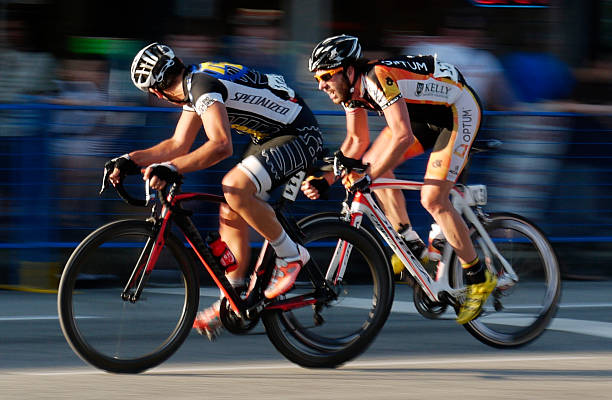 One pro Cyclists Overtakes another in the evening sun Burnaby, Canada - July 12, 2012: One cyclist glances at his pursuer as he is about to be overtaken during the 2012 Giro di Burnaby cycle racing stock pictures, royalty-free photos & images