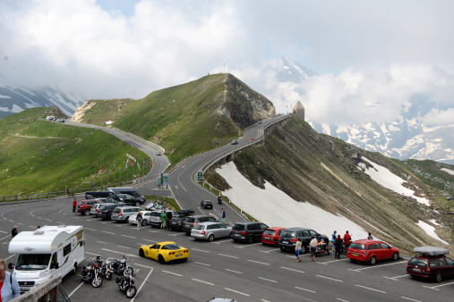 Grossglockner, Austria - July 21, 2013: Parking on a viewing platform on the Grossglockner High Alpine Road (Salzburg, Austria). Cars parked on the edge. People wander around and enjoy the view.