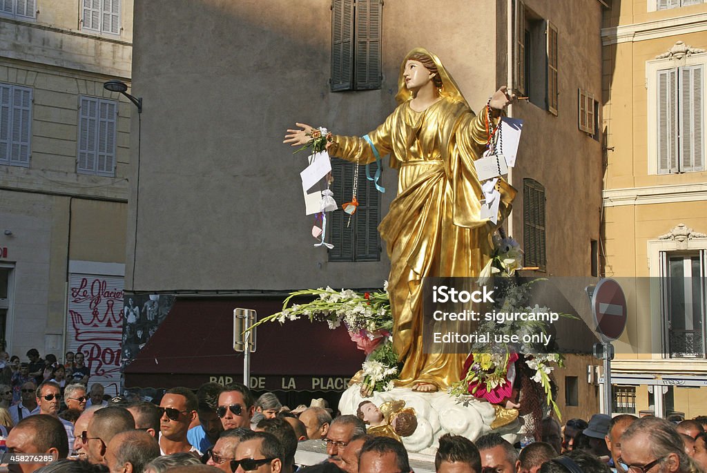Statue of the virgin Mary, Assumption procession in Marseille, France. Marseille, France - August 15, 2013 : People escorting the statue of the virgin Mary during the annual Assumption procession in Marseille, France. Every year on mid-August the Christian population parades through the streets of "Le Panier" district of Marseille escorting a statue of the Madonna on a big litter as a sign of devotion. Here the parade is in Lenche Square.Statue of the virgin Mary, Assumption procession in Marseille, France. The Feast of the Assumption of the Blessed Virgin Mary Stock Photo