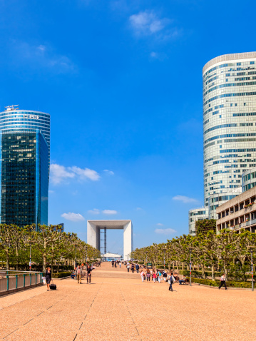 Paris, France - May 21, 2010: Tourists resting on the grass in the central square of La Defense, in the background is The Big Arch monument.