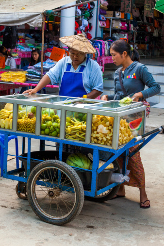 Tachileik, Myanmar - December 13, 2011: Fruit vendors at a street market. The town is a popular destination for travellers making a visa run from Thailand, and Thai people looking for cheap goods from Myanmar.