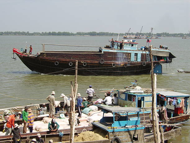Vinh Xuong, Vietnam - February 21, 2008: trespassing Vietnam border. Local people working on wooden fishing boats. In the background another one ascending the Mekong river through Cambodia.