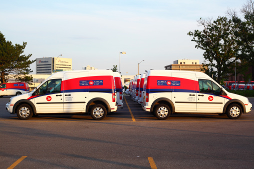 Toronto, Ontario, Canada - June 26, 2013: Canada Post fleet vehicles standing near the office in line (two rows) - side view