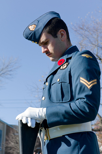 Dartmouth, Canada - November, 11 2012: Wearing his poppy, a member of Canada's Armed Forces (Airforce) stands at attention during the Remembrance Day service in Dartmouth Nova Scotia.  Hundreds of people turn out each year at this cenotaph to remember those that have fallen during times of war.