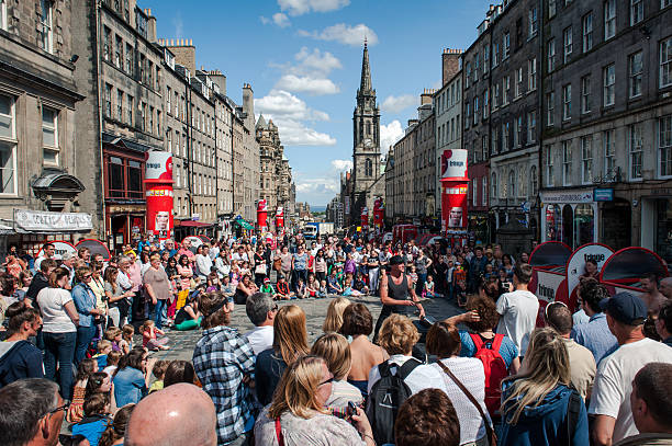 Edinburgh, United Kingdom - July 30, 2013: People assist at the performance of a street artist on the Royal Mile in Edinburgh, during a sunny day before the official launch of the Fringe Festival.The Edinburgh Fringe Festival is the world's largest arts festival.