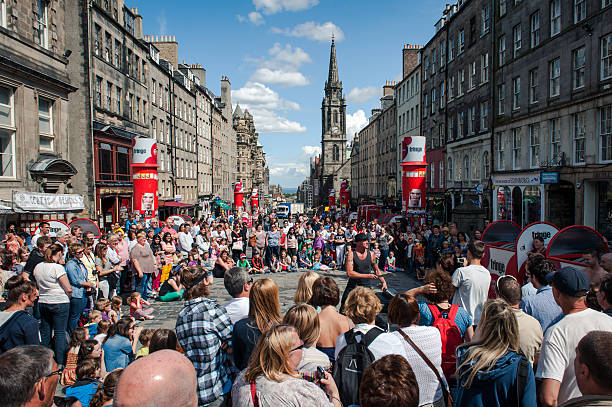People on the streets of Edinburgh Edinburgh, United Kingdom - July 30, 2013: People assist at the performance of a street artist on the Royal Mile in Edinburgh, during a sunny day before the official launch of the Fringe Festival.The Edinburgh Fringe Festival is the world's largest arts festival. royal mile stock pictures, royalty-free photos & images