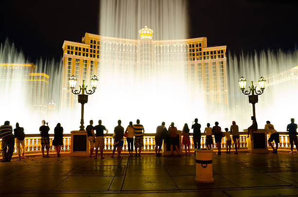 Fountains of Bellagio Las Vegas, USA - August 12, 2012: Musical fountains at Bellagio Hotel and Casino. The Bellagio opened October 15, 1998, it was the most expensive hotel ever built at US$1.6 billion. People leaning over the wall to watch the fountains at night. bellagio stock pictures, royalty-free photos & images