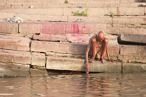 Old man sittng at border of Ganges in Varanasi stock photo