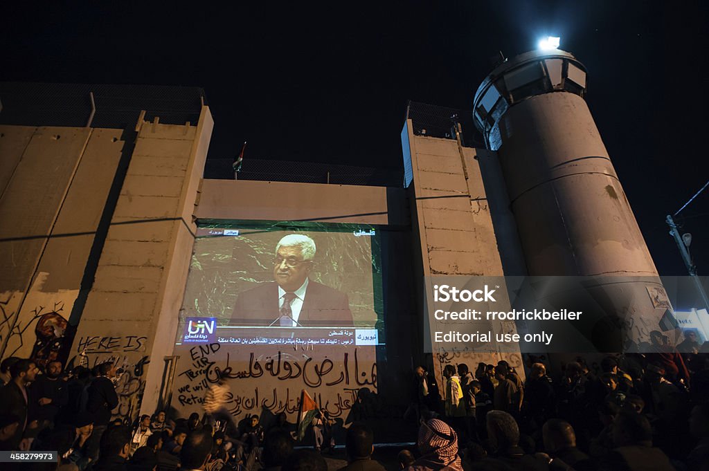 Mahmoud Abbas speech for Palestinian UN bid on Israeli wall Bethlehem, Occupied Palestinian Territories - November 30, 2012: Hundreds of Palestinians gather to watch the speech by Prime Minister Mahmoud Abbas in the bid for Palestine's "nonmember observer state" status at the United Nations, projected on the Israeli separation wall in the West Bank town of Bethlehem, November 29, 2012. Hours later, the UN General Assembly voted 138-9 in favor of the upgraded status for Palestine, with 41 nations abstaining. Mahmoud Abbas Stock Photo