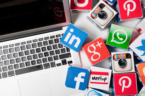 London, United KIngdom- September 24, 2013: Apple laptop alongside social media logos printed onto handmade cubes. Logos include google plus, Facebook and Linkedin. Social media uses web and mobile technology to connect people