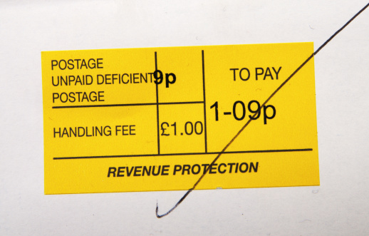 Helston, Cornwall, UK - November 8, 2013: A label showing the amount payable for unpaid postage on an item of post before the Royal Mail will deliver it. The label is marked Revenue Protection.