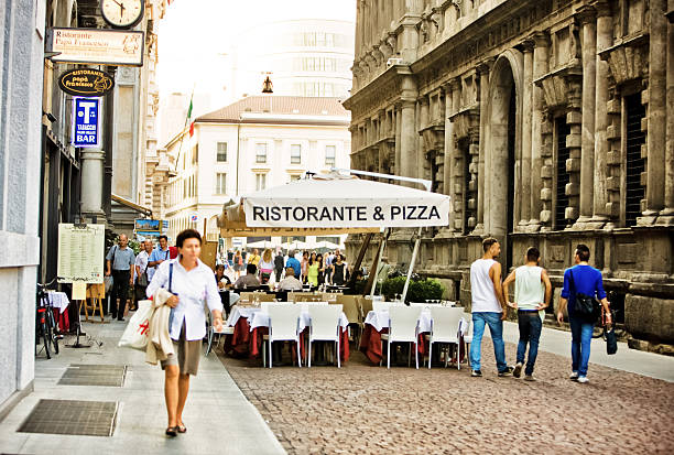 Milan, Italy  - October 4, 2011: Restaurant and Pizzeria at Piazza della Scala, Milan. Covered Tables are waiting for customers. People passing along. Restaurant is called \