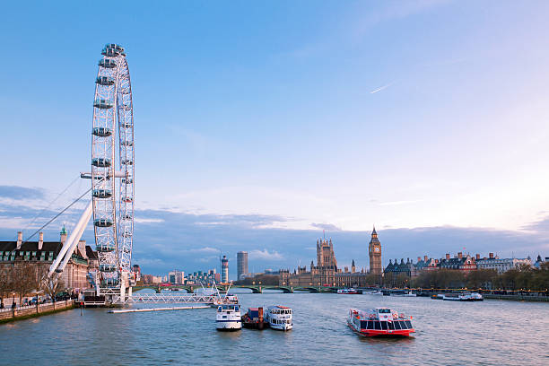 London, England, United Kingdom- April 14, 2012: London eye side view with Big Ben at dusk. London Eye is the largest Ferris wheel in Europe, structure of the London Eye is 135 M. tall and the wheel has a diameter of 120 M.