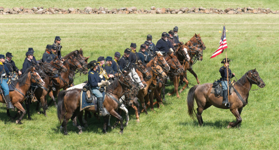 Gettysburg, Pennsylvania, USA - July 6, 2013: Federal Cavalry ride with battle flags flying high at a reenactment commemorating the 150th anniversary of the American Civil War (1861-1865).