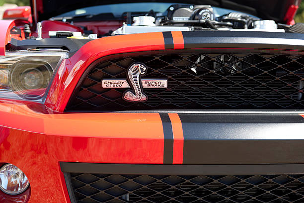 Arlington, United States - July 13, 2013: This image shows a beautiful red and black striped Shelby Cobra Mustang on display at a public car show. Image highlights the front grille and logo.