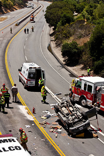 Monterey, California, USA. June 29, 2013: An overturned SUV (sport utility vehicle) on a two-lane highway, with emergency vehicles and crews, and helicopter ambulance in the background.
