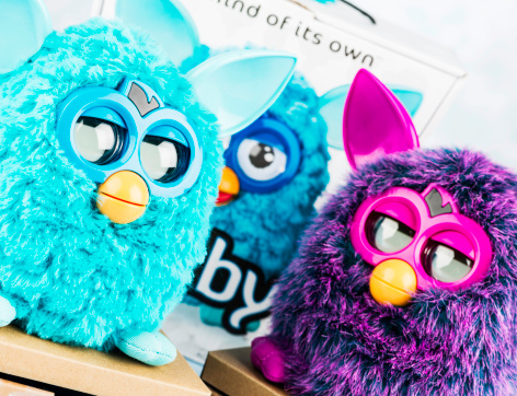 Suffolk, Virginia, USA - November 14, 2012: A horizontal studio shot of two Furby toys standing on the original platform they were shipped with. Behind the toys is the original packaging for the teal Furby. Furbys are a battery operated electronic toy, made by Hasbro that perform various moves and communicates in a 