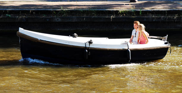 Amsterdam, The Netherlands- August 28, 2013: A young couple enjoying a romantic boat tryp aorund the canals of Amsterdam on a very warm and sunny summer day.