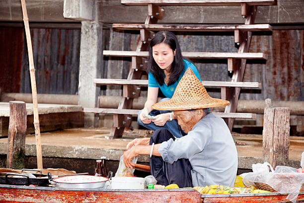 Damnoen Saduak Damnoen Saduak, Thailand-August 9, 2009: An elderly woman sells food from his boat at a floating market near Bangkok mode of transport rowing rural scene retail stock pictures, royalty-free photos & images