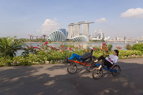 Singapore, Singapore - October 27, 2013: Two women on recumbent bicycles cycle along a track at Gardens by the Bay East, with Gardens by the Bay, Marina Bay Sands and the Singapore CBD in the background.