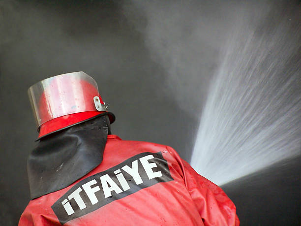 Ankara Fire Fighter Team person extinguishing Ankara , Turkey - October 15, 2004: The burning building is "Sivrihisar Association Headquarters" at "Sıhhiye", Ankara. A fire fighter who's Ankara City Fire Fighter team was extinguishing the fire. Man wore his protective clothes and firefighter's helmet. 2004 2004 stock pictures, royalty-free photos & images