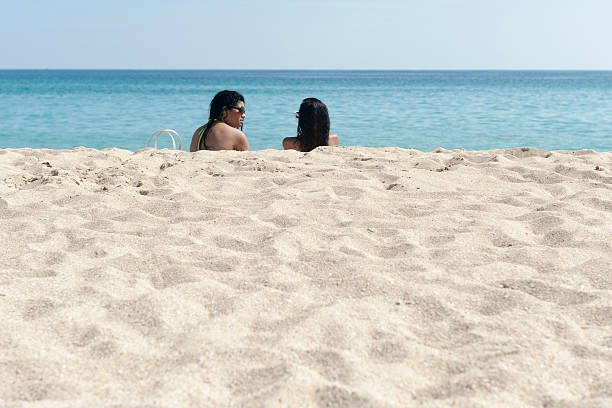 havana, A!uba - June 13, 2013: two beautiful cuban ladies are sitting on the beach on a sunny day in havana