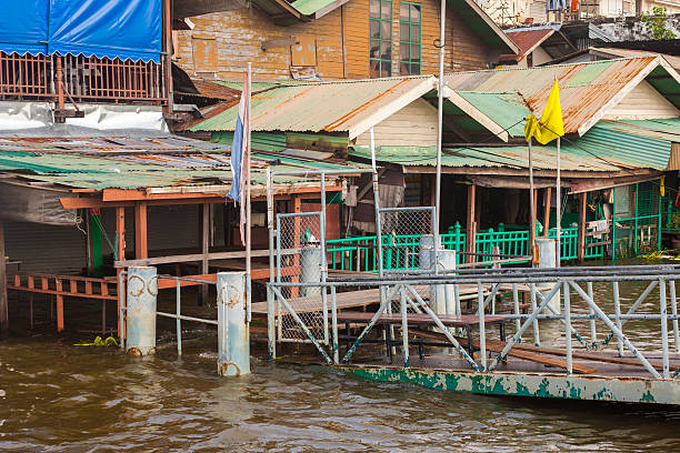 Bangkok, Thailand - October 14, 2011: Bangkok waterfront showing the rising water in the Chao Phraya River opposite Wat Arun. Buildings along the waterfront can be seen partly submerged, while a restaurant that is partly submerged continues to operate. A pier that leads to a ferry stop can be seen partly submerged.