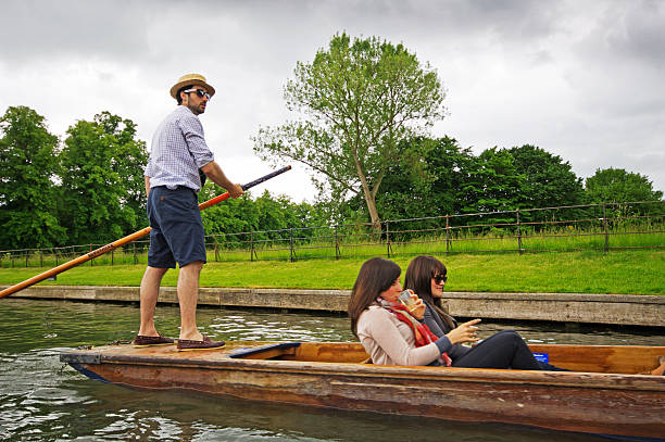 Punting on the Cam Cambridge, United Kingdom - June 16, 2013: Lazy Sunday afternoon on the River Cam in Cambridge, England, tourists on punts with tourists looking on. couple punting stock pictures, royalty-free photos & images