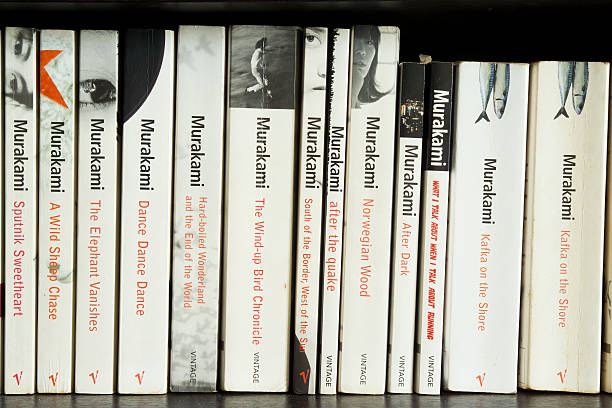 Haruki Murakami Novels Singapore, Singapore - August 23, 2013: A paperback collection of Haruki Murakami's fiction and non-fiction titles on a dark wood bookshelf.  Published by Vintage Publishing, these English translations of best-selling author Murakami's works have all designed with a minimalist black-and-white cover. book title stock pictures, royalty-free photos & images