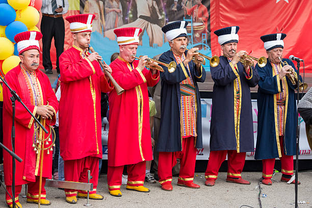 A young man humorously dressed as a medieval nobleman holding a red boombox, set against a vibrant yellow background, blending historical costume with modern pop culture.