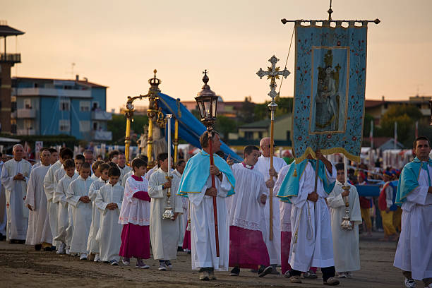 Caorle; religious procession Caorle, Italy - 12 september 2010: The procession is about to end, she came from the sea by fishing boats, at this time is on the beach.We see the crucifix, the banner of the portrait of the Virgin Mary, the priests, the children to follow you can see the statue of the Madonna and the rest of the procession. monsignor stock pictures, royalty-free photos & images