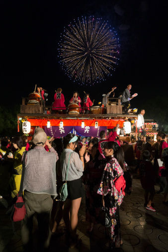 Nagoya, Japan - July 20, 2013 : People at the summer festival in Nagoya Port, Nagoya, Aichi Prefecture, Japan. The decorated float is for the night parade in the summer festival. Fireworks light up in Nagoya Port.