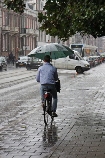 Amsterdam, The Netherlands - 16th September 2011: Gentleman cycles down a path in the pouring rain
