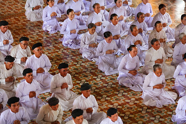 молиться, мужчин и женщин в cao worshipping dai храм - caodaiism стоковые фото и изображения