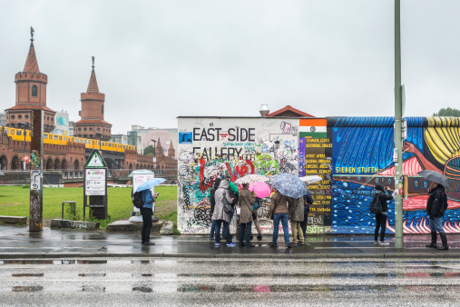 Berlin, Germany - September 24, 2013: Tourists walking along the East Side Gallery, an international memorial for freedom with 105 paintings by artists from all over the world on a 1,3 km long section of the Berlin Wall.