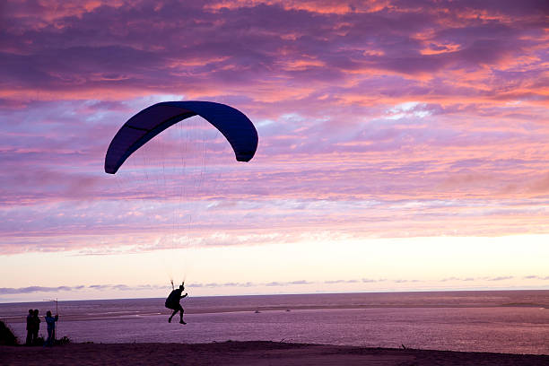 Arcachon, France - June 17, 2013. View to the Bay of Arcachon (Bassin d'Arcachon) at sunset. A paraglider takes off from the Great Dune of Pyla (Dune du Pyla), Europe's tallest sand dune. Some people on the left watching this picturesque moment.