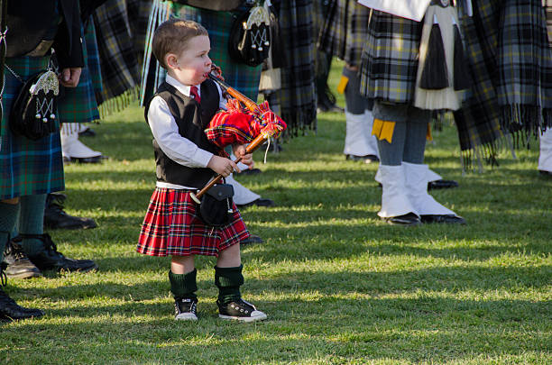 Young bagpiper  boy in kilt and hose West Point, NY., April 14, 2013: A young boy, with toy bagpipes, and wearing tartan kilt, joins the massed bagpipe bands at the US Military Academy for the closing service at then end of the bagpipe Tattoo event hosted by the US Army Academy Cadet Band. kilt stock pictures, royalty-free photos & images