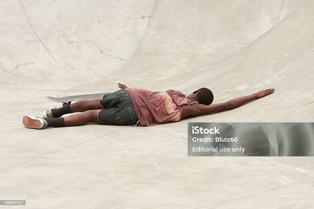 Adolescent pose sur béton après s'essuyer durant skate Run - Photo de Accident bénin libre de droits
