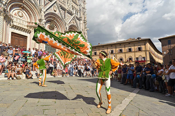 Selva city neighborhood figures waving their flags Siena, Italy - August 16, 2011: "Selva" city neighborhood figures parade in front of Siena's Cathedral, few hours before the beginning of the race. torre del mangia stock pictures, royalty-free photos & images