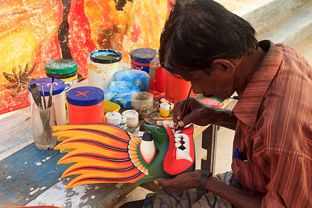 Man Painting a Mask Sri Lanka, Colombo - October 29, 2013: A man is painting a fire devil mask. It's traditional fire devil mask in exotic countries. It's supposed to subdue enemies and bring friendship or harmony. sri lankan culture stock pictures, royalty-free photos & images