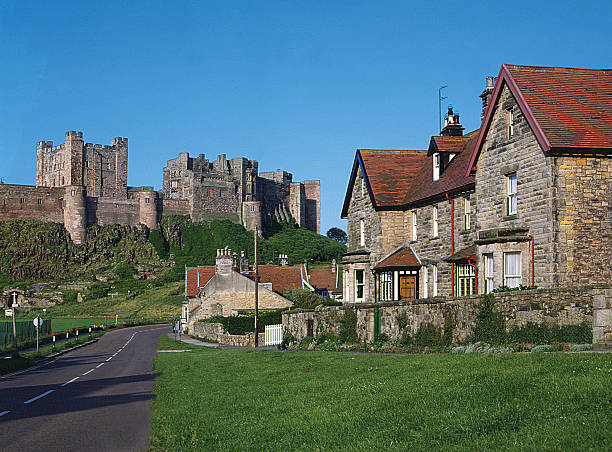 деревня и замок бамбург northumberland, англия - bamburgh стоковые фото и изображения