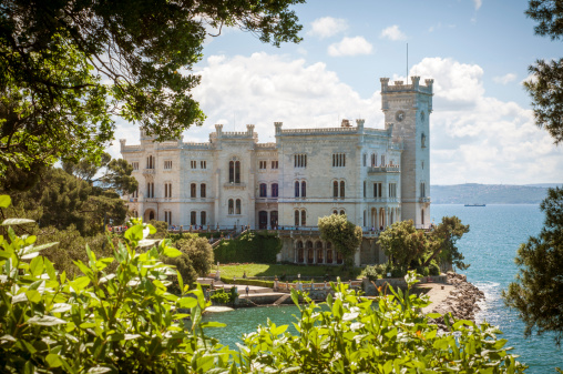 Trieste, Italy - May 18, 2013: Miramare Castle (Castello di Miramare) photographed through a treetop in nice and sunny day.