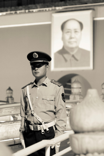 Beijing, China - May 23, 2013: Soldier standing against Forbidden City southern gate at night. The balcony with Mao's portrait on Tian-An-Men square is a symbol of China. In monochrome.