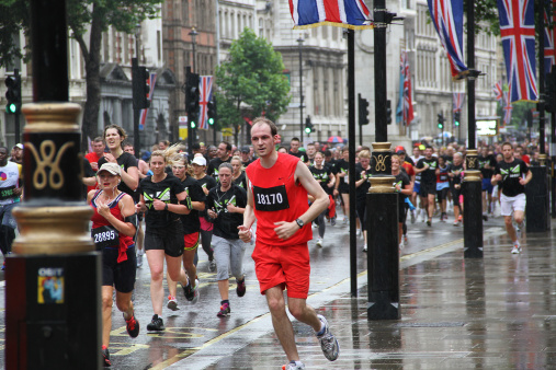 London, England - July 08, 2012: A colour photograph of runners at the 2012 British London 10K, the lamp posts are decorated with the union jack. 300,000 runners participated and it was sponsored by Nike & Tiger Balm. The run starts at wellington arch and ends at Whitehall towards Trafalgar square. runners pass some very famous places including Big BenHouses of Parliament, The London Eye, St Paulaas Cathedral, Trafalgar Square, Nelsonaas Column andWestminster Abbey.
